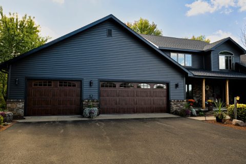 Blue house with a three-car garage and landscaped driveway.