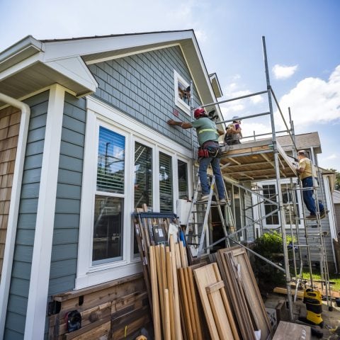 Workers installing new siding on a house exterior during renovation project.