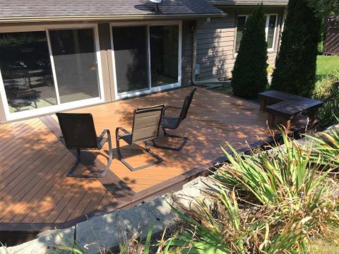 Outdoor wooden deck with chairs and garden view.