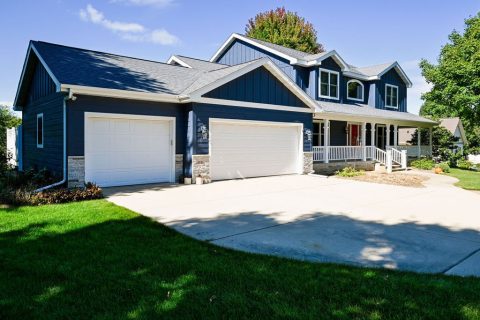 Beautiful blue house with a two-car garage and well-maintained lawn.