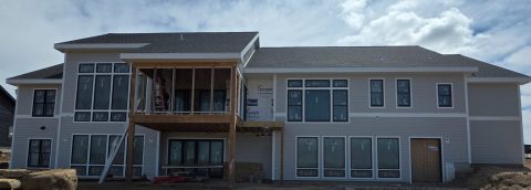 Modern house with new siding and large windows under construction.
