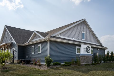 New blue and gray house siding with a gable roof and landscaped yard.