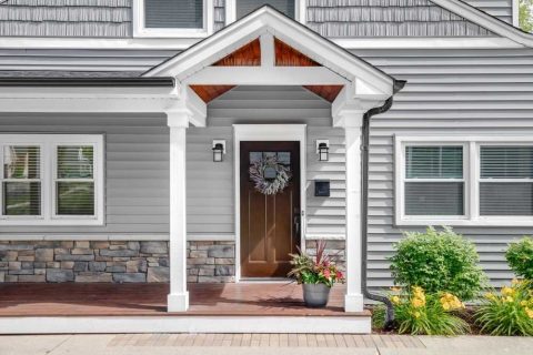 Contemporary house with siding, front porch, and decorative wreath on door.