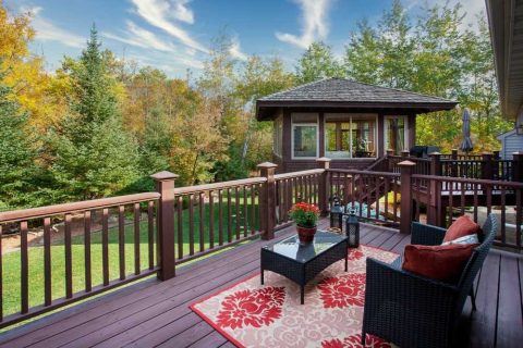 Outdoor deck with seating and scenic forest view in autumn.