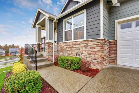 Exterior view of a house with large windows, a garage door, and landscaped front yard.