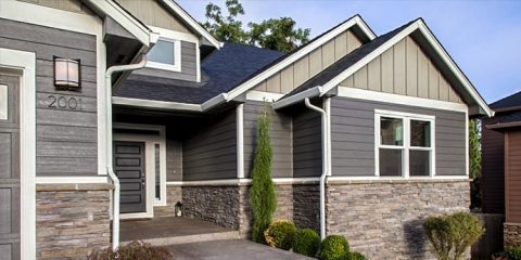 Contemporary home featuring gray siding, stone foundation, and white trim details.