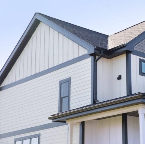 Contemporary house with white siding and gray trim, featuring a gable roof and window details.