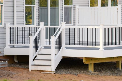 Modern white deck with black railing and stairs for outdoor living.