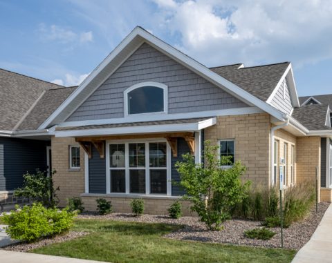 Beautiful modern house with brick and siding exterior and landscaped yard.