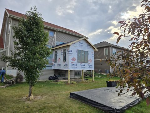 House undergoing exterior remodeling with new siding and window installation.