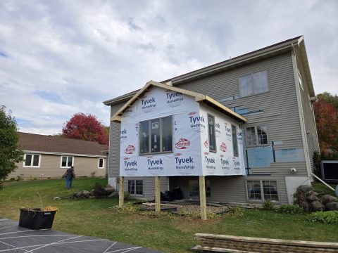 Newly constructed porch with insulation and framing on a residential house.
