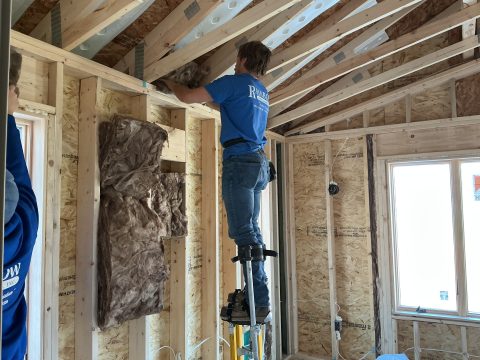 Worker installing insulation in an attic during interior remodeling.
