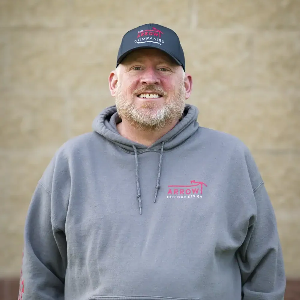 Smiling man in gray hoodie and cap with Arrow Exteriors logo.