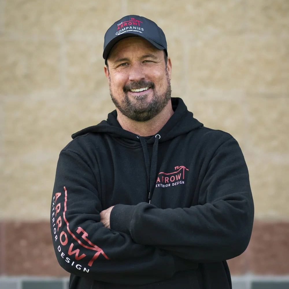 Smiling Arrow Exteriors employee in black hoodie and cap.