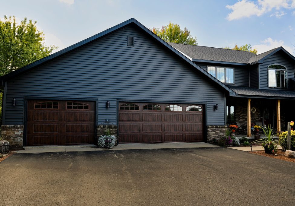 Blue house with a three-car garage and landscaped driveway.
