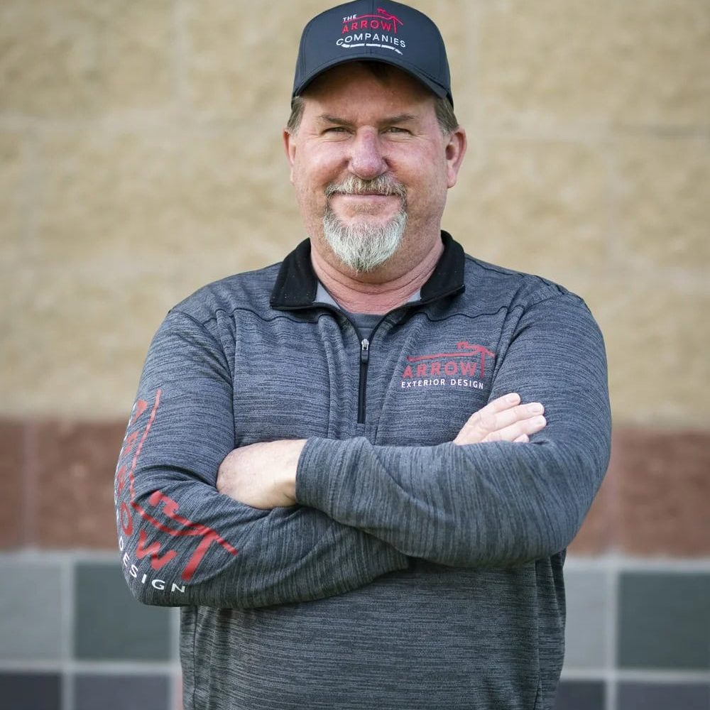 Portrait of a smiling Arrow Exteriors team member in front of a building.